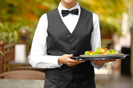Young waitress with salad in restaurantの写真素材