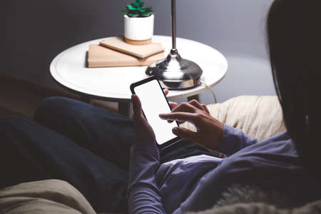 Young woman with mobile phone at home late in evening