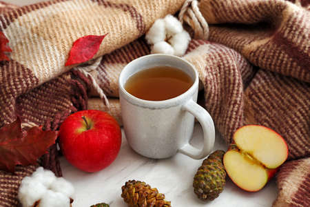 Cup of hot tea with plaid on white table