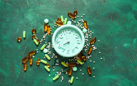 Clock and many different pills on color backgroundの写真素材