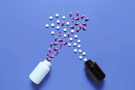 Jars and different scattered pills on color backgroundの写真素材