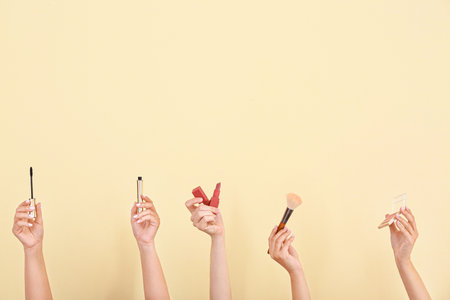 Many hands with decorative cosmetics and brush on color backgroundの写真素材