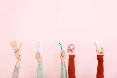 Female hands with supplies for hair removing on color backgroundの写真素材