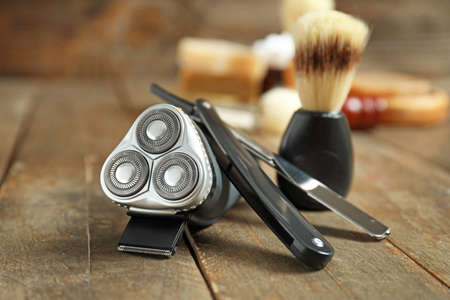 Electric shaver with razor and brush on wooden tableの写真素材