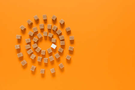 White sugar cube among brown ones on color background. Concept of uniquenessの写真素材