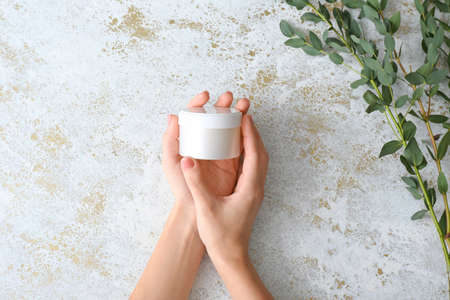 Female hands with jar of cream on light backgroundの写真素材