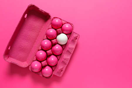 White egg among pink ones in package. Concept of uniquenessの写真素材