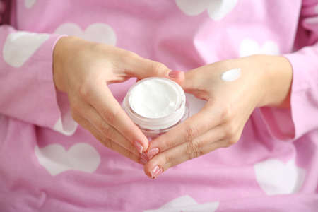 Young woman with jar of hand cream, closeupの写真素材