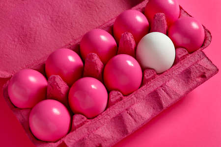 White egg among pink ones in package. Concept of uniquenessの写真素材