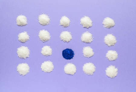 Blue sugar among white ones on color background. Concept of uniqueness