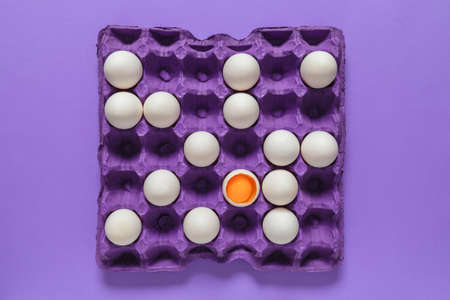 Broken egg among whole ones in package. Concept of uniqueness
