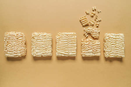 Crushed noodles among whole ones on color background. Concept of uniqueness