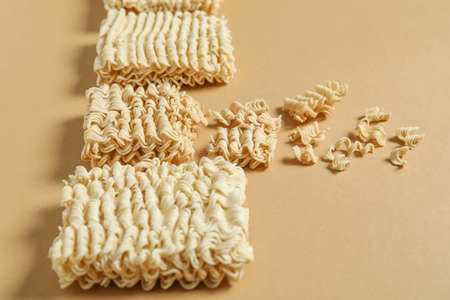 Crushed noodles among whole ones on color background. Concept of uniqueness