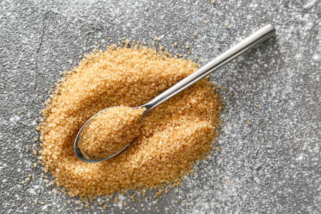 Spoon and heap of brown sugar on gray backgroundの写真素材