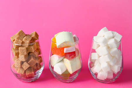 Glasses with sugar and sweets on color background