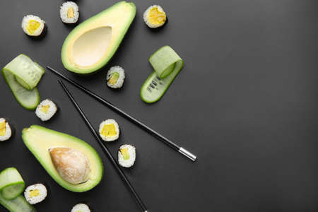 Composition with tasty sushi and avocado on dark background
