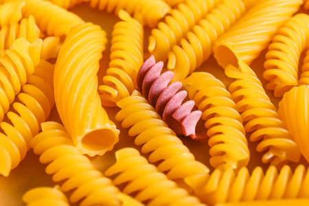 One pink pasta among others. Difference and uniqueness concept