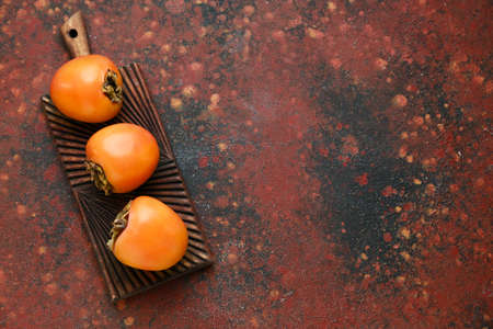 Board with ripe persimmons on grunge backgroundの写真素材