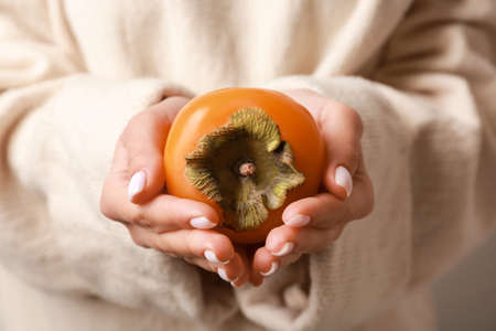Woman holding ripe persimmon, closeupの写真素材