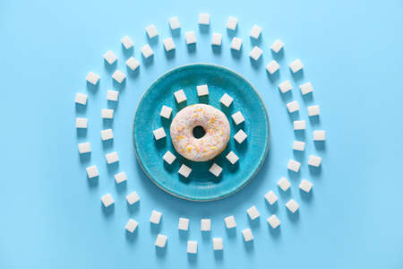 Plate with donut and sugar on color backgroundの写真素材