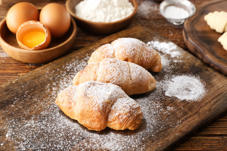 Baked croissants with sugar powder on wooden boardの写真素材