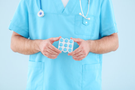 Male doctor with pills on light backgroundの写真素材