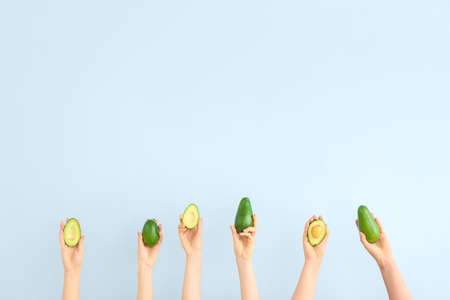 Female hands with fresh avocados on light backgroundの写真素材