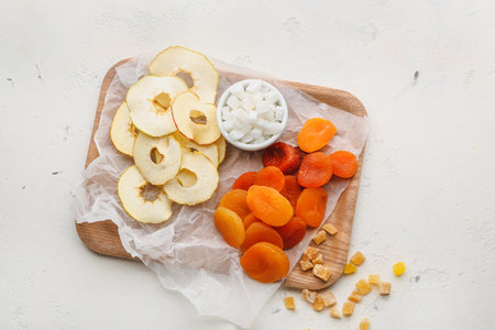 Board with different dried fruits on light backgroundの写真素材