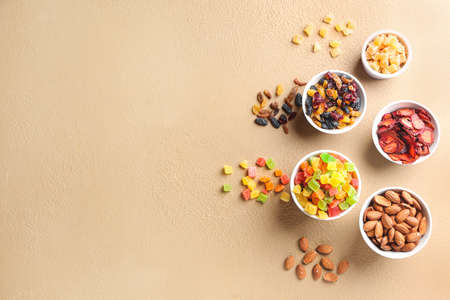 Bowls with different dried fruits and nuts on color backgroundの写真素材