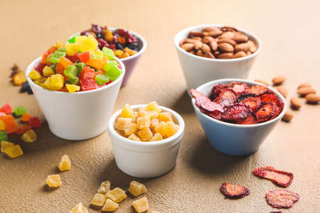 Bowls with different dried fruits and nuts on color backgroundの写真素材
