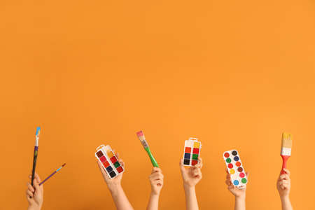 Female hands with painter's supplies on color backgroundの写真素材