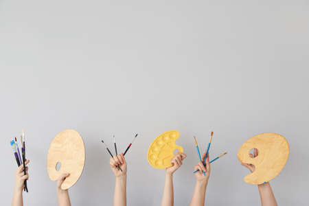 Female hands with painter's supplies on gray backgroundの写真素材