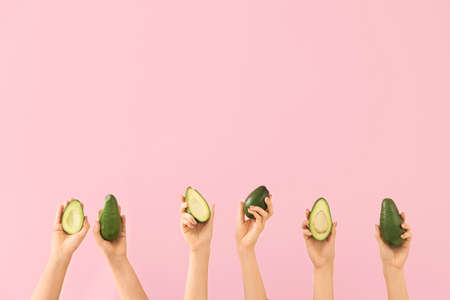 Female hands with fresh avocados on color backgroundの写真素材