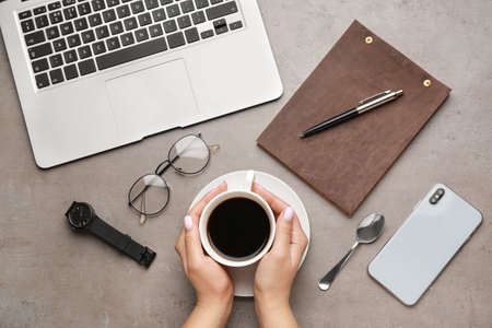 Woman drinking hot coffee at workplace, top view