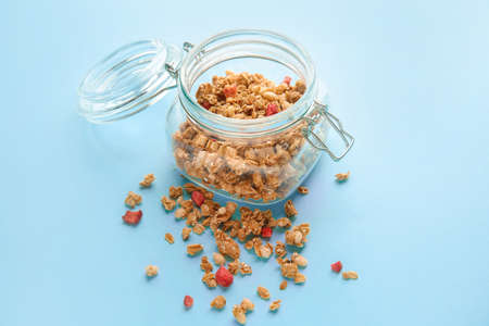 Jar with tasty granola on color background