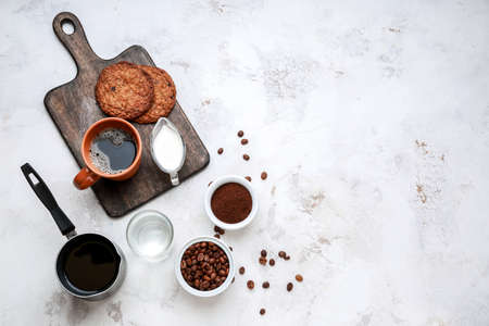 Cup of hot coffee with milk and cookies on light backgroundの写真素材