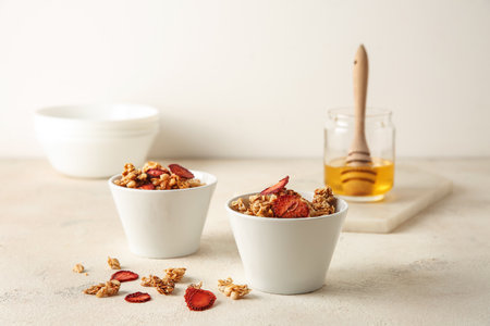 Bowls with tasty granola and berries on white tableの写真素材