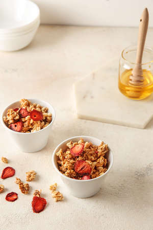 Bowls with tasty granola and berries on white tableの写真素材