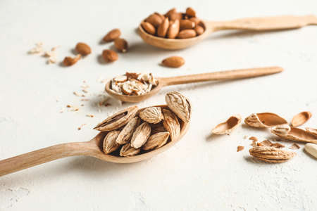 Spoons with tasty almonds on white backgroundの写真素材