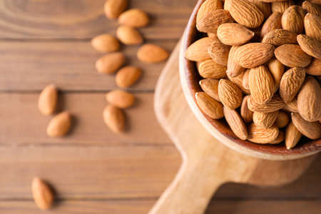 Bowl with tasty almonds on wooden tableの写真素材