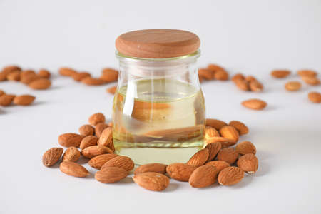 Tasty almond oil with nuts on white background
