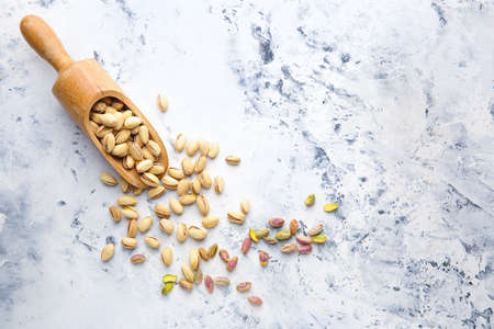 Scoop with tasty pistachio nuts on white backgroundの写真素材