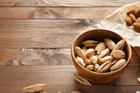 Bowl with tasty almonds on wooden tableの写真素材