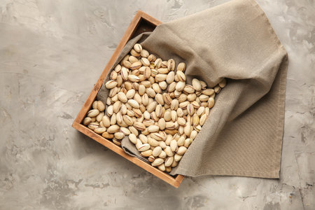 Tray with tasty pistachio nuts on grunge background
