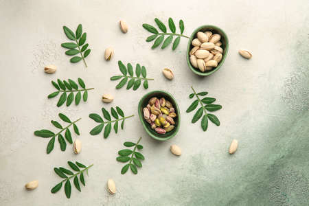 Bowls with tasty pistachio nuts on light backgroundの写真素材