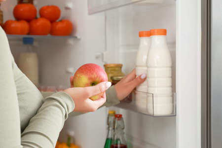 Woman taking food out of fridge