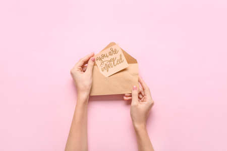 Female hands with invitation and envelope on color backgroundの写真素材