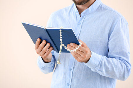 Muslim man with Koran and beads on light background, closeupの写真素材