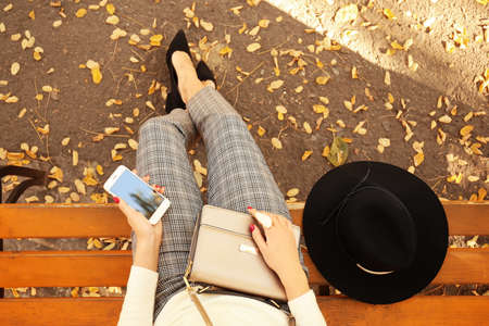 Beautiful young woman sitting on bench in autumn park