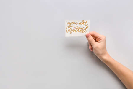 Female hand with invitation on light backgroundの写真素材